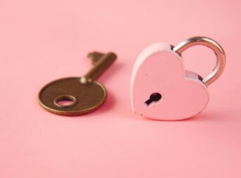 a heart shaped lock and a key on a pink background